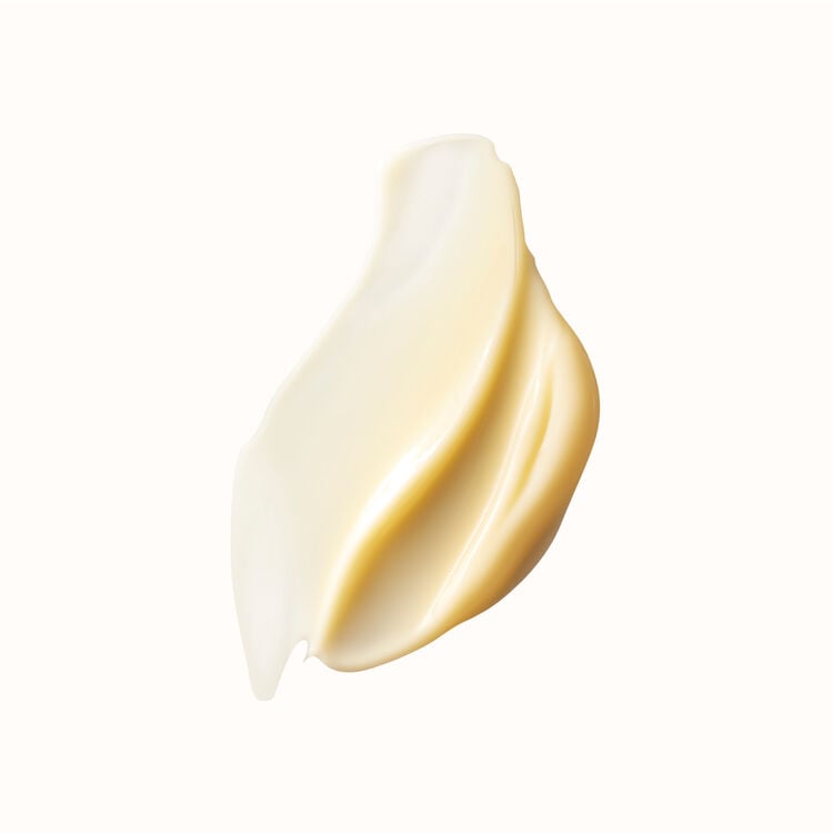 A creamy, light yellow cosmetic product smear with distinct ridges and highlights, photographed against a stark white background.
