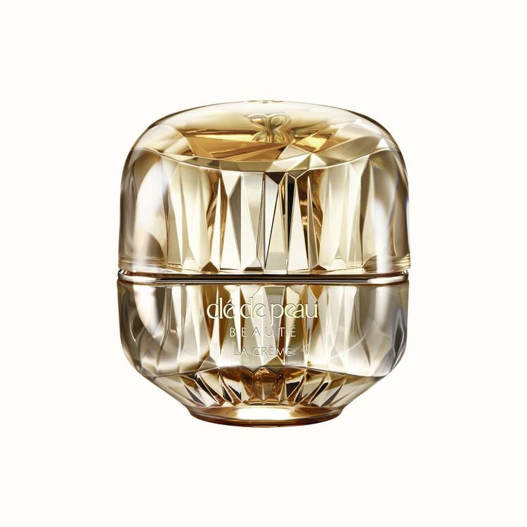 A luxurious gold faceted jar of Clé de Peau Beauté La Crème, isolated on a white background.