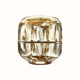 A luxurious gold faceted jar of Clé de Peau Beauté La Crème, isolated on a white background.