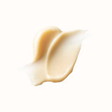 A dollop of thick, creamy, pale peach-colored skincare product with a subtle sheen is smeared across a white background.