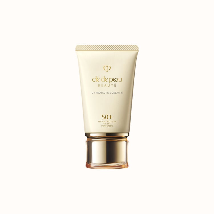 A tube of Clé de Peau Beauté UV Protective Cream with SPF 50+, in an elegant cream-colored tube with a gold cap.