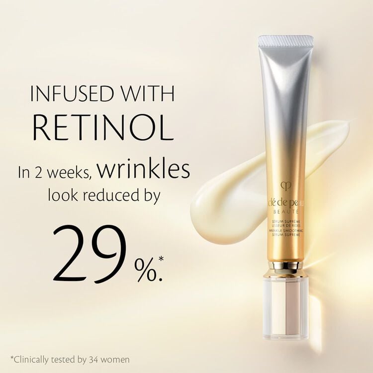 A metallic gold-and-silver tube of skincare cream standing upright against a soft beige background, with a glossy, cream-like swirl behind it. Text reads "Infused with Retinol. In 2 weeks, wrinkles look reduced by 29%*. *Clinically tested by 34 women."