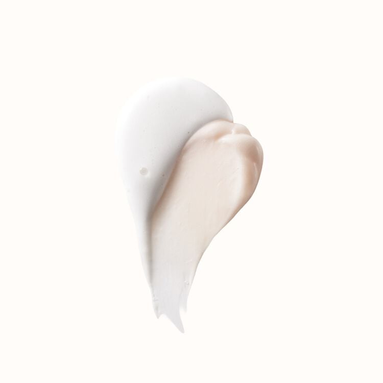 Two creamy swatches of beauty product, one white and one light peach, layered on a white background.