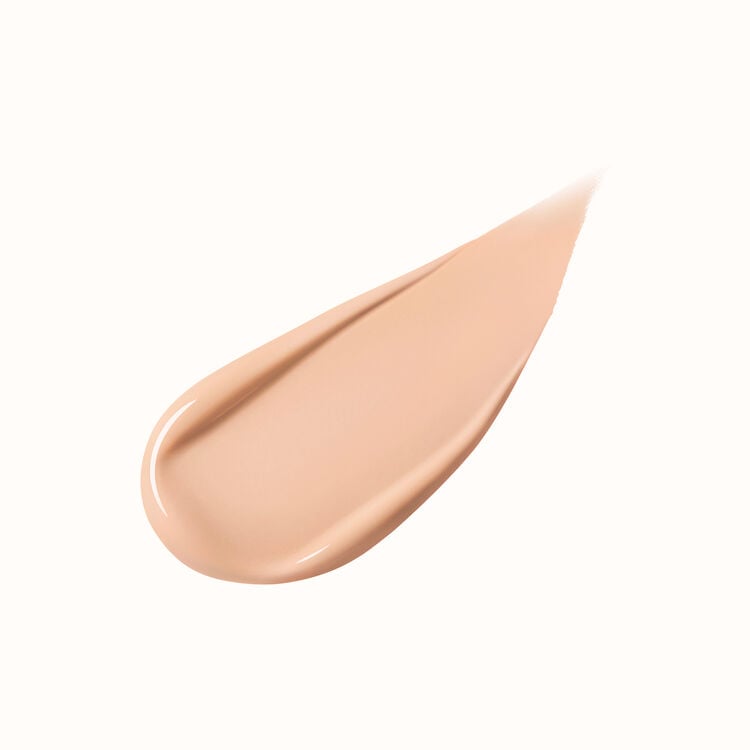 A pear-shaped swipe of light-colored liquid foundation, slightly thicker at one end and tapering to a point, against a white background.